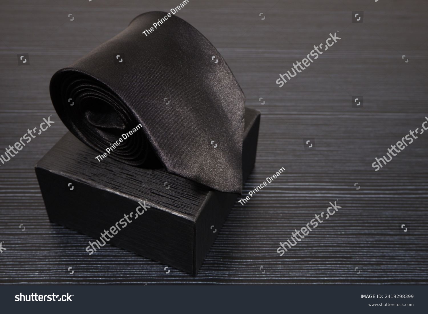 Black tie rolled on black gift box close up view, Black on black concept, Copy space, Single object  #2419298399