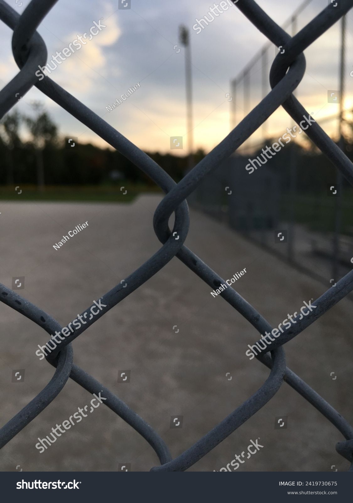 A chainlink fence with a baseball diamond in the background. #2419730675