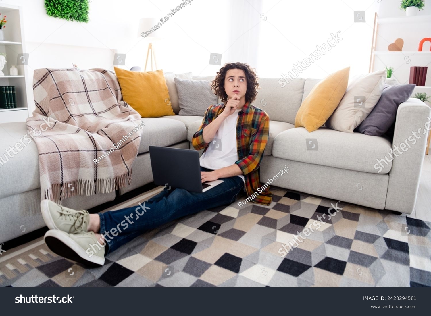 Full length photo of uncertain unsure guy dressed checkered shirt texting modern gadget indoors house home room #2420294581