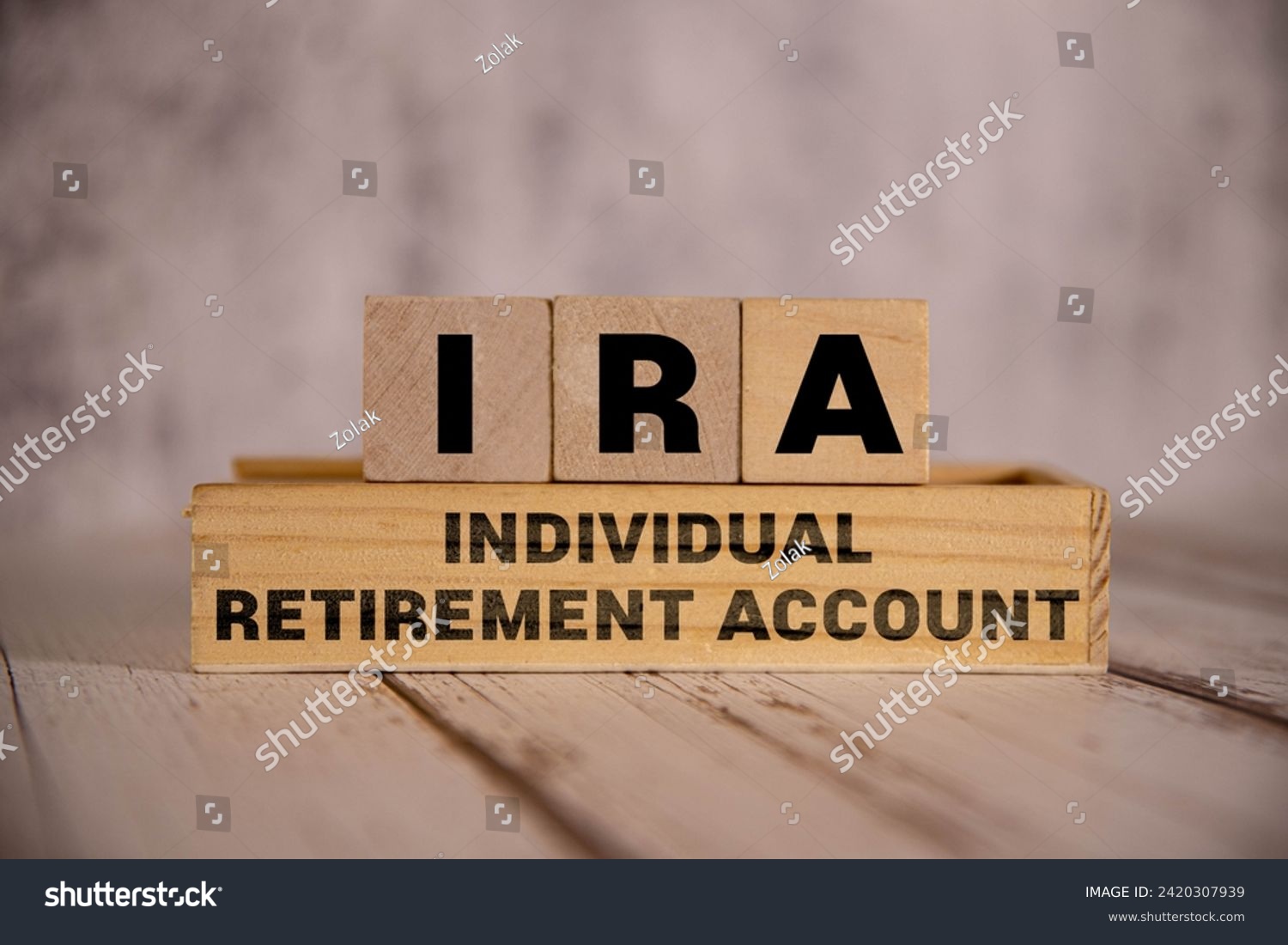 On a bright blue background, light wooden blocks and cubes with the text IRA Individual Retirement Account. #2420307939