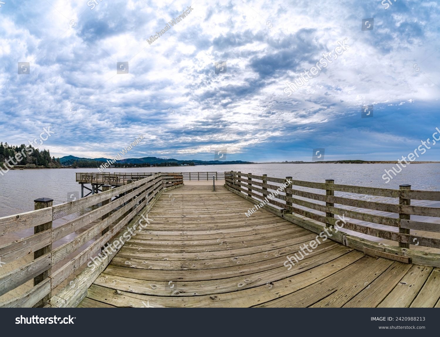Old wooden pier over bay ocean waters with beautiful sunny sky and sandy beach in panoramic format. No data licensing. #2420988213