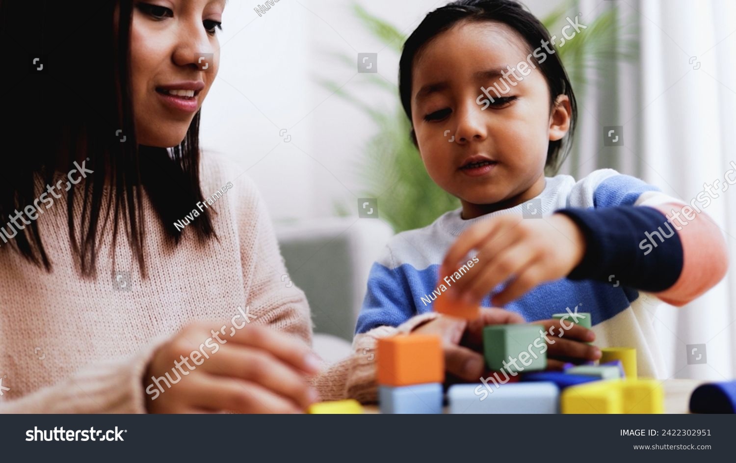 Latin American mother and son child having fun playing games with wood toy bricks at home. Education and family leisure time concept #2422302951