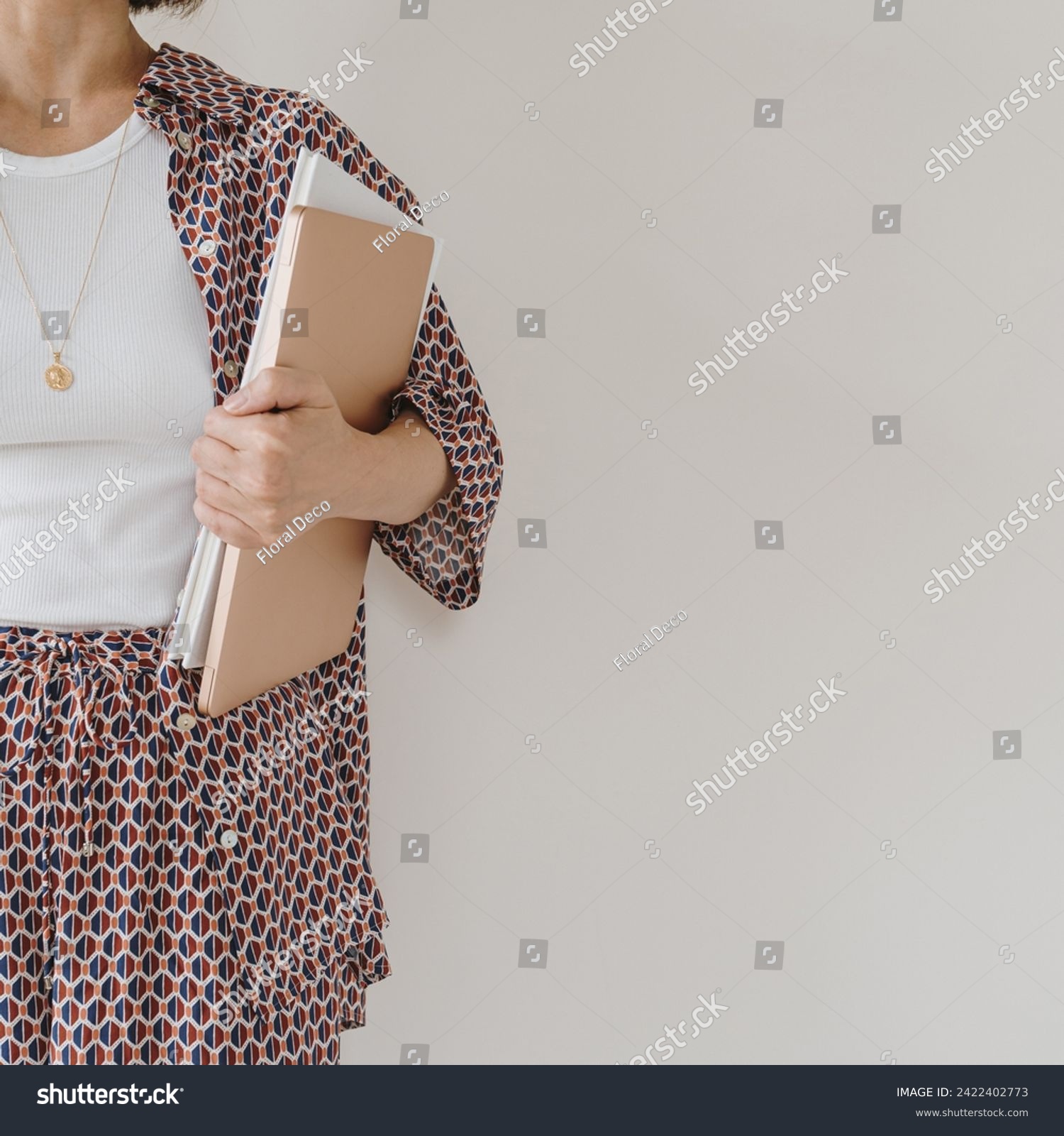 Laptop computer and paper documents in female hand. Young pretty woman in pajamas stays over white wall. Businesswoman, work at home concept #2422402773