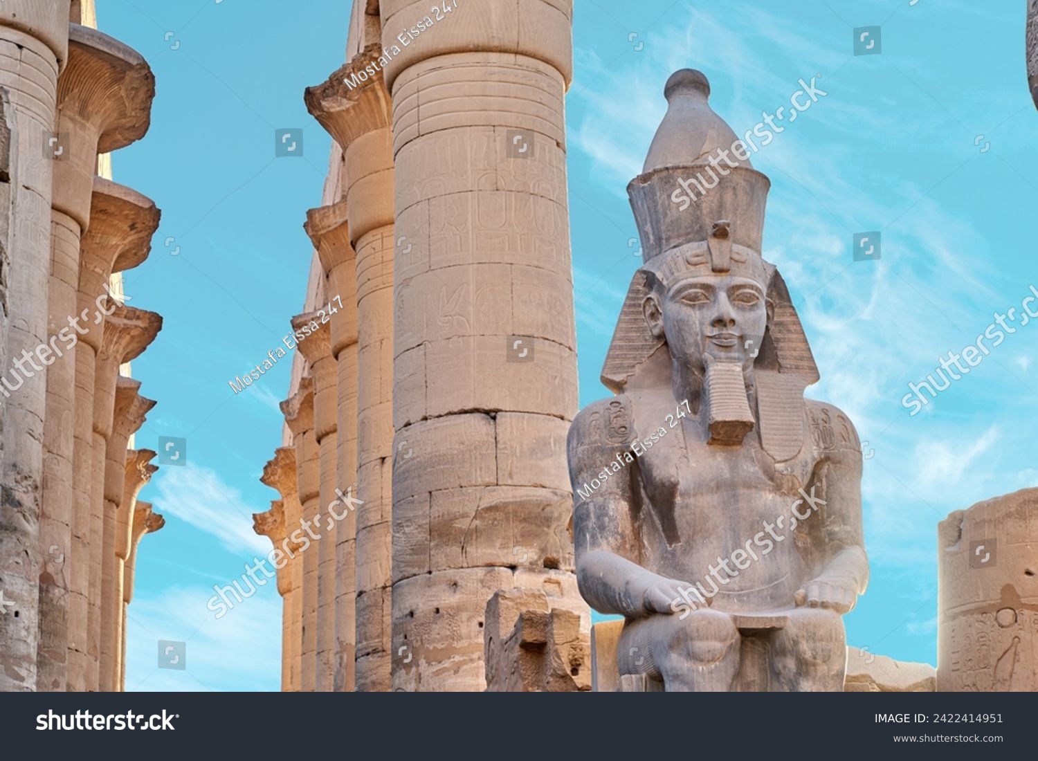 Seated statue of Ramesses II by the First pylon of the Luxor Temple, Egypt. Columns and statues of the Luxor temple main entrance, first pylon, Egypt #2422414951