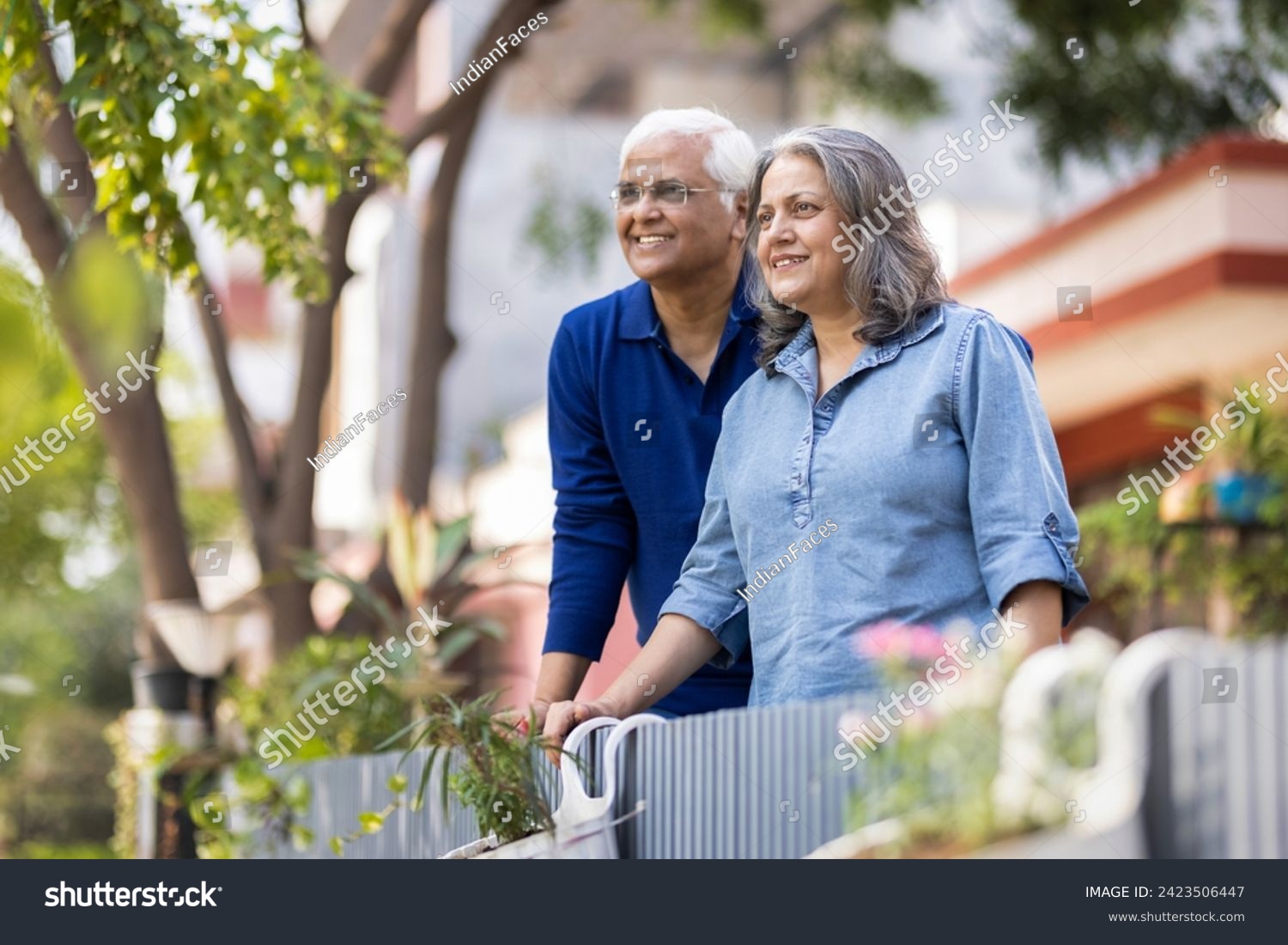 Smiling Indian senior couple with hands clasped looking away #2423506447