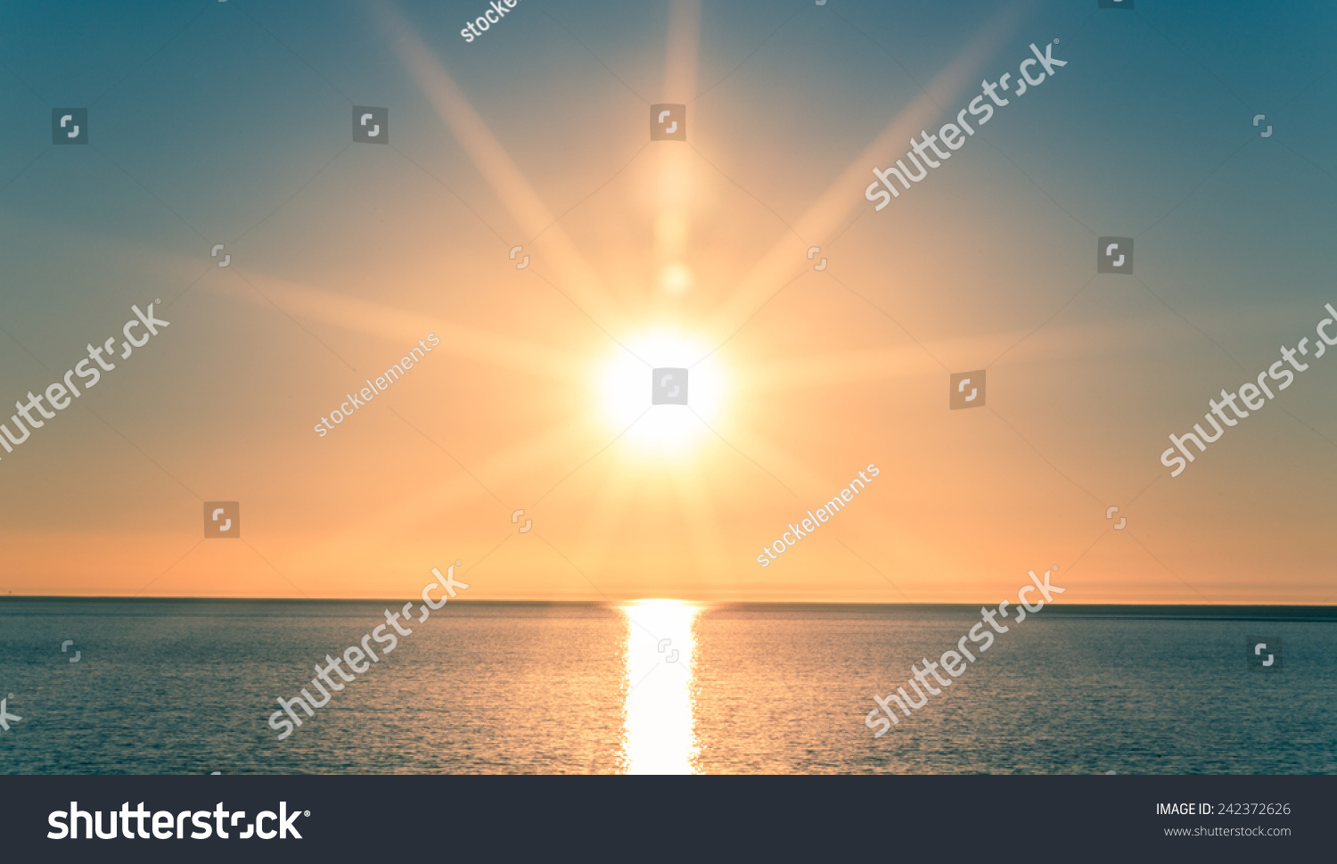 Sunset over Ocean - Bright Orange Sun Setting on Beautiful Blue Water #242372626