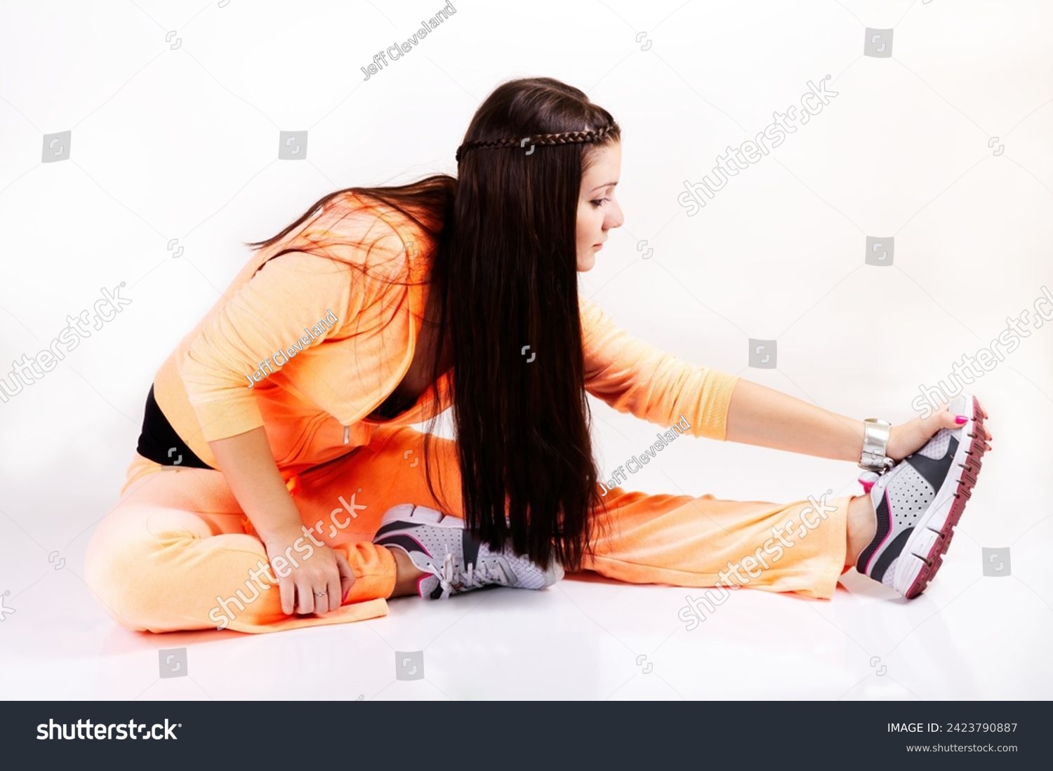 Young Caucasian Woman Sitting On White Background Stretching Out Wearing An Orange Sweat Suit #2423790887