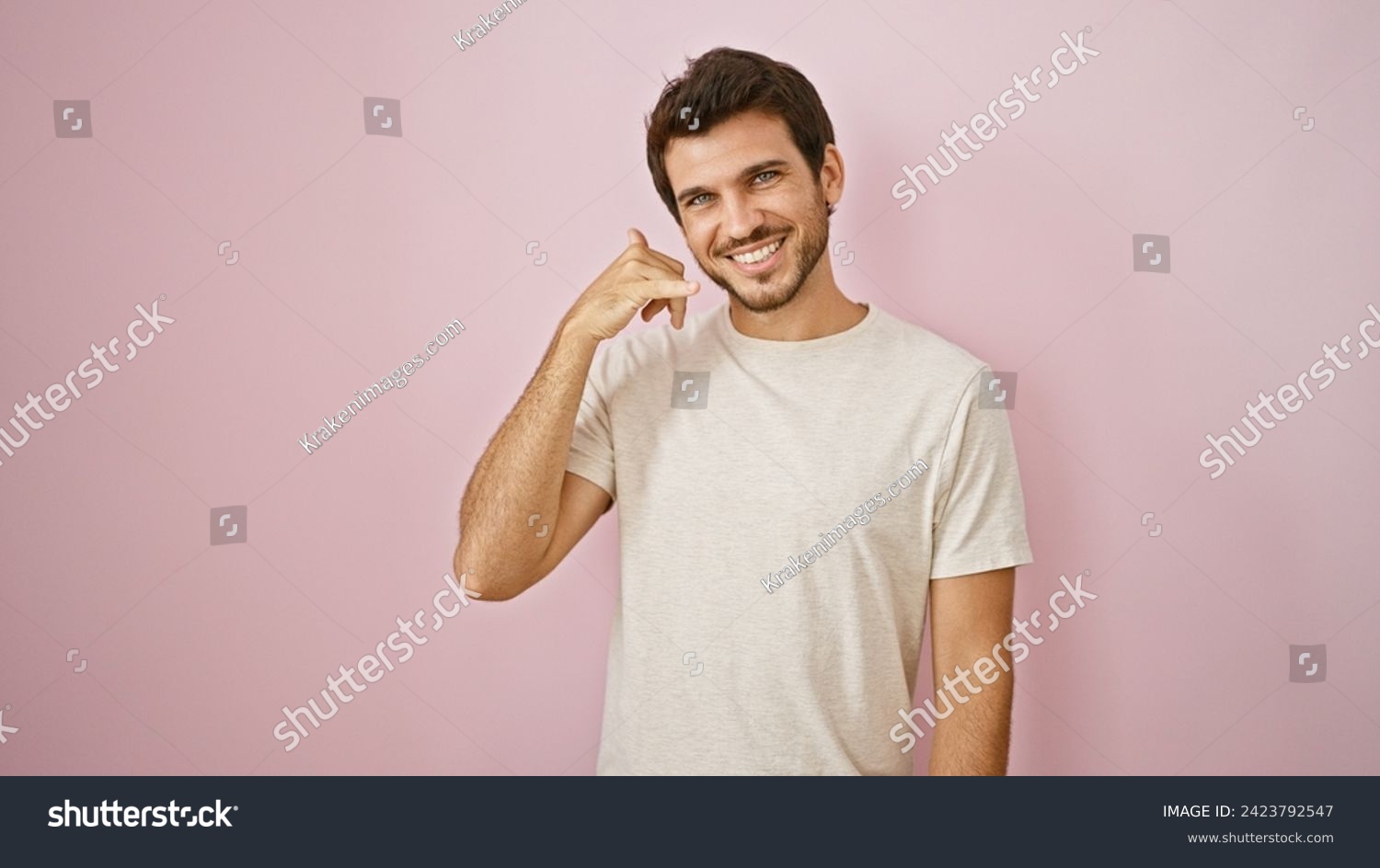 Smiling young hispanic man with beard making call me gesture against a pink isolated background #2423792547
