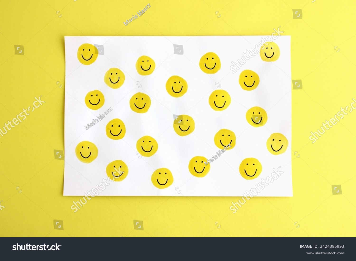 Many happy yellow smileys handpainted on white card on a bright yellow background - authentic image representing the concept of positive emotions, happiness, positive vibes, energy, motivation, fun #2424395993