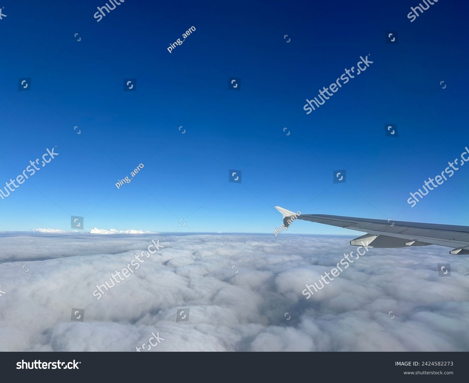 An airplane wing with winglet in the blue sky above the clouds, captured from the airplane window #2424582273