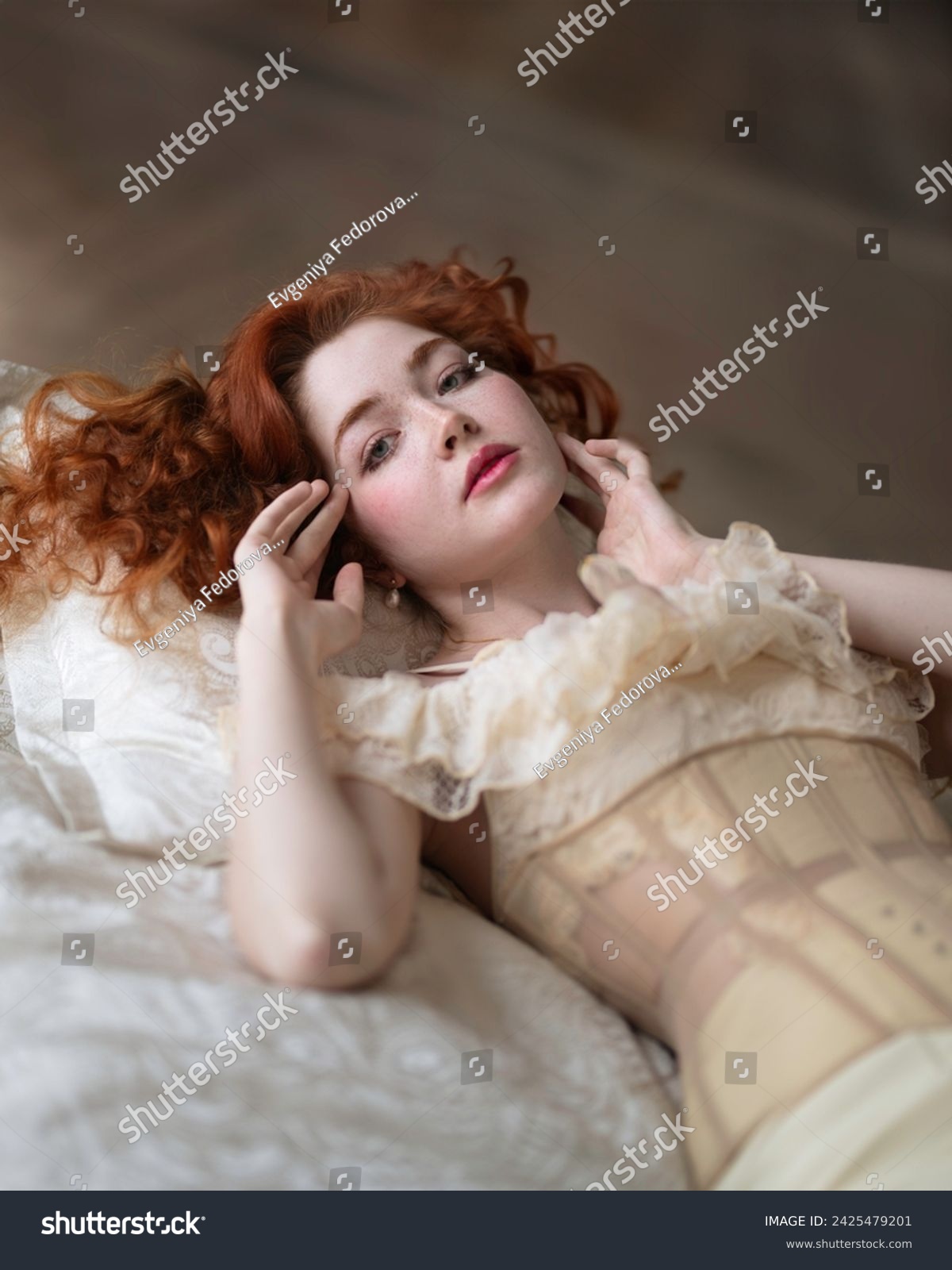 A girl with long red hair in a lace chemise with a corset lies on the bed #2425479201