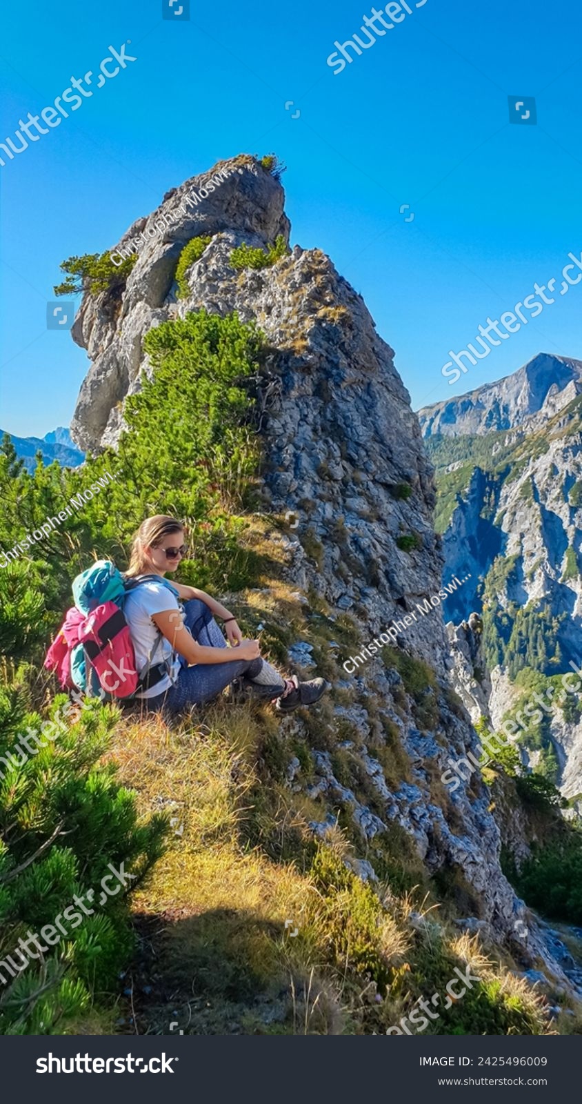 Hiker woman resting next to unique rock formation with panoramic view of majestic Hochschwab massif, Styria, Austria. Idyllic hiking trail in remote Austrian Alps. Sense of escapism, peace, reflection #2425496009