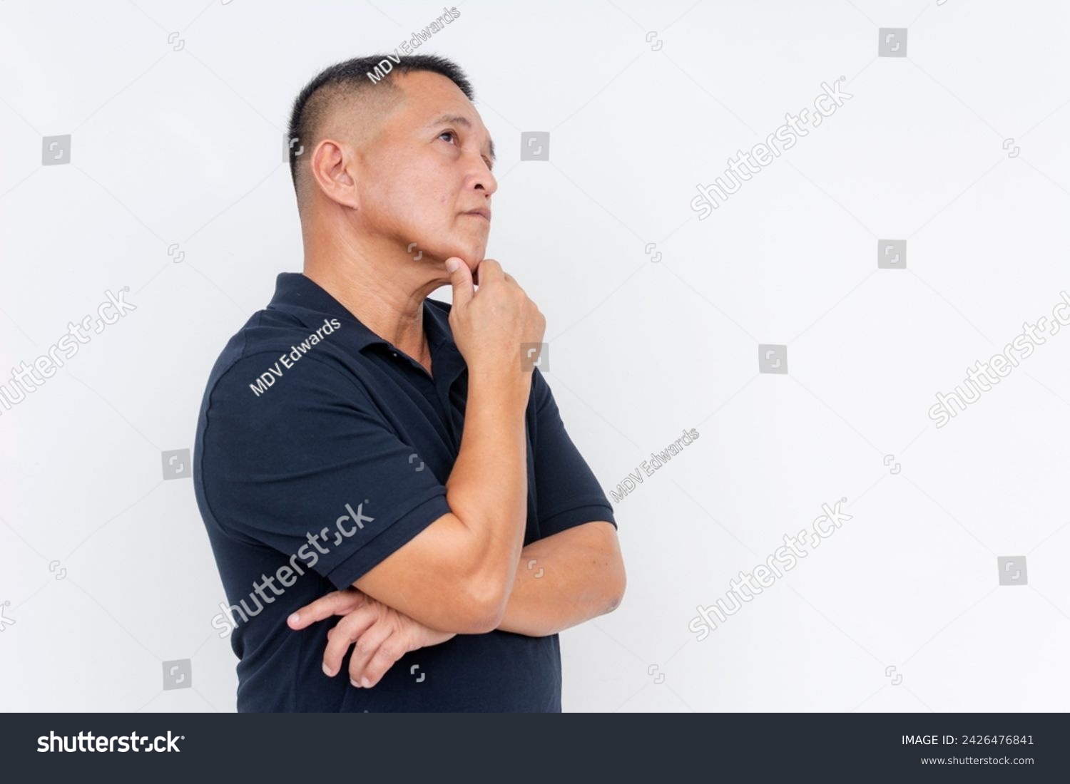 Side view of a contemplative middle-aged Asian man looking upwards, hand on chin, isolated over a white background, pondering. #2426476841