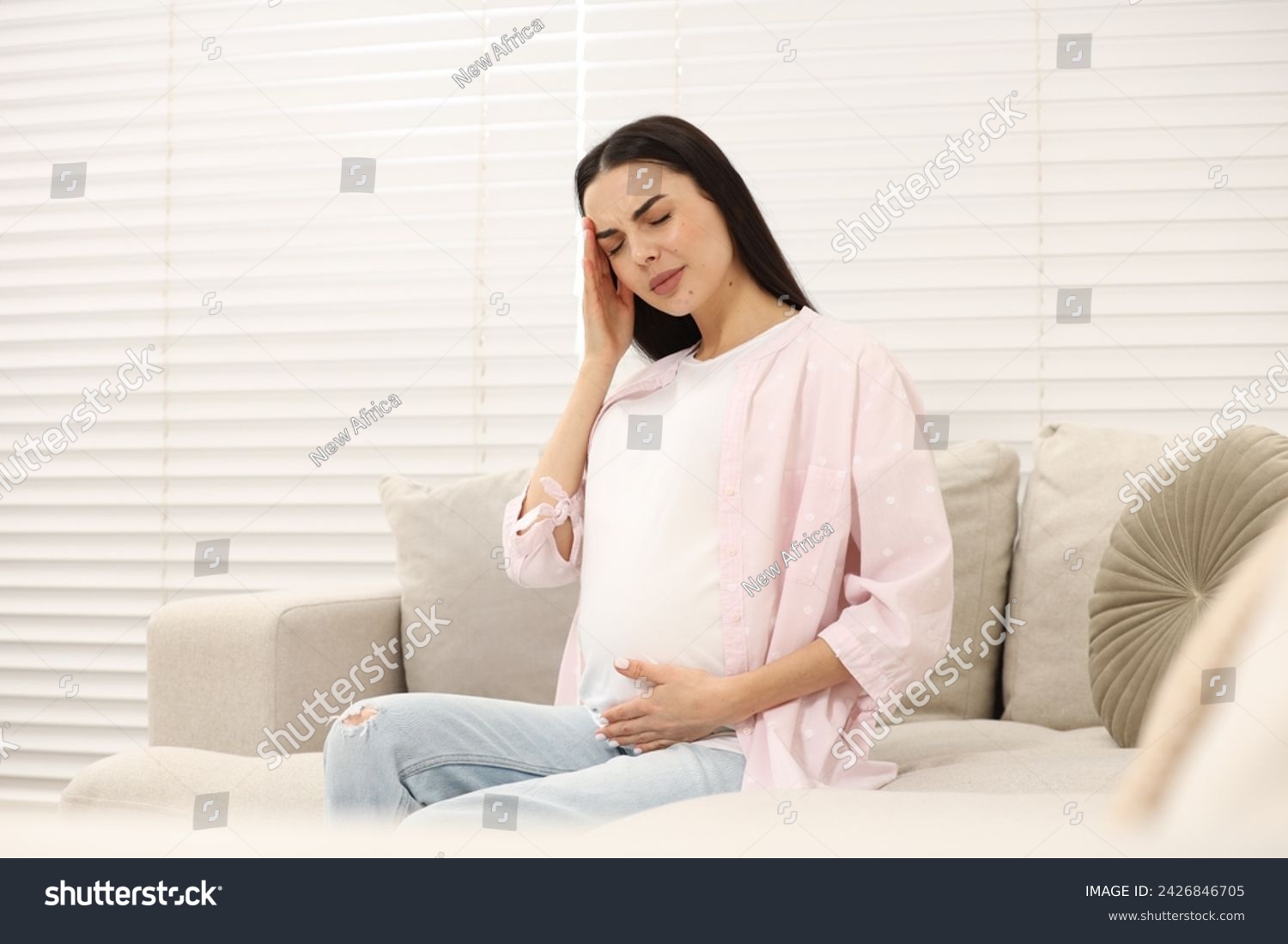 Pregnant woman suffering from headache on sofa at home #2426846705