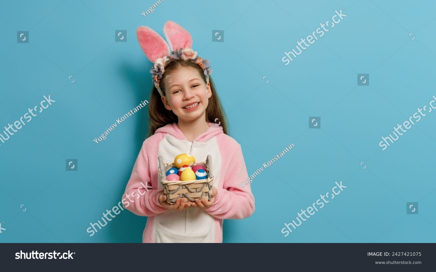 Cute little child wearing bunny ears on Easter day. Girl with painted eggs. #2427421075