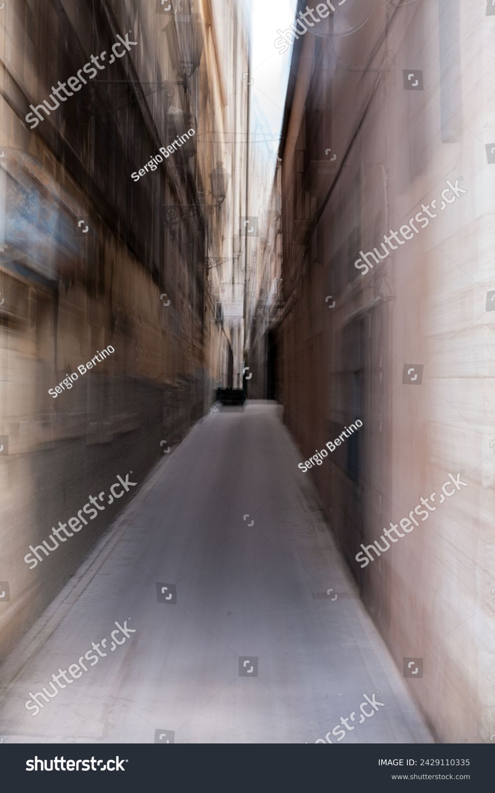 Long deserted narrow passage between two urban buildings with a concrete floor and diminishing perspective #2429110335