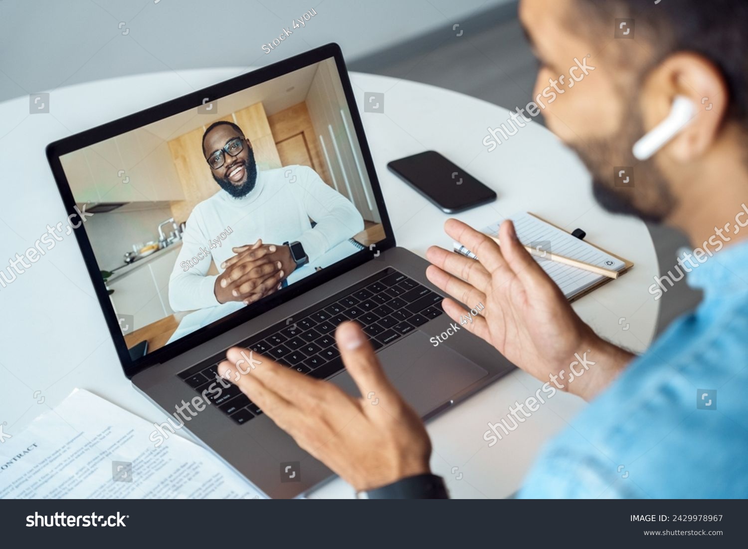 american man talking using webcam internet connection. Millennial indian arabian student speaking with teacher business coach mentor sitting at home desk. Video conference app. View over shoulder #2429978967