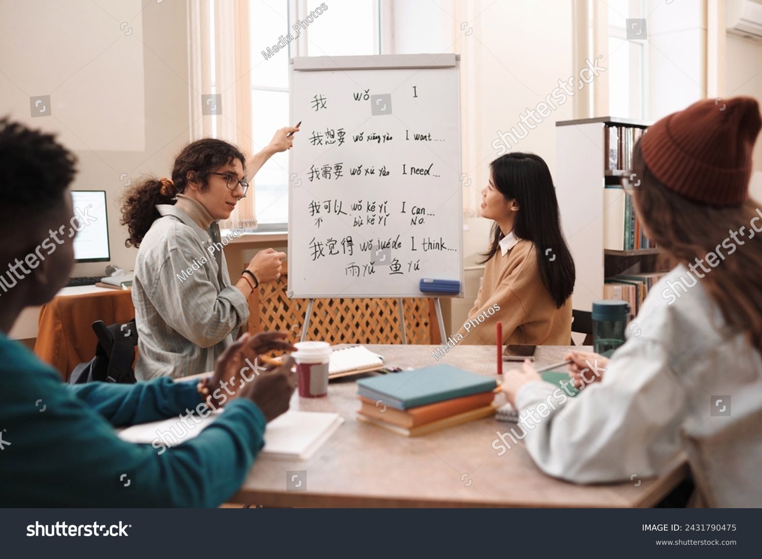 Side view portrait of male student answering questions during Chinese language class and pointing at whiteboard with hieroglyphs #2431790475