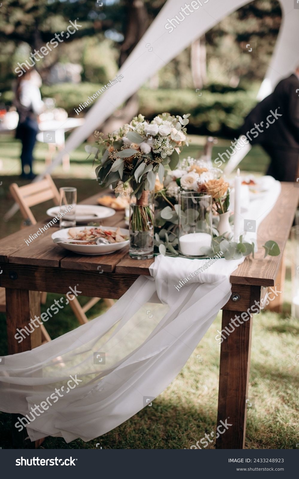 Many small pink and white flower arrangements with roses, eustoma and various flowers in clear glass vases. On the festive table in the wedding banquet area, compositions of flowers and greenery, cand #2433248923