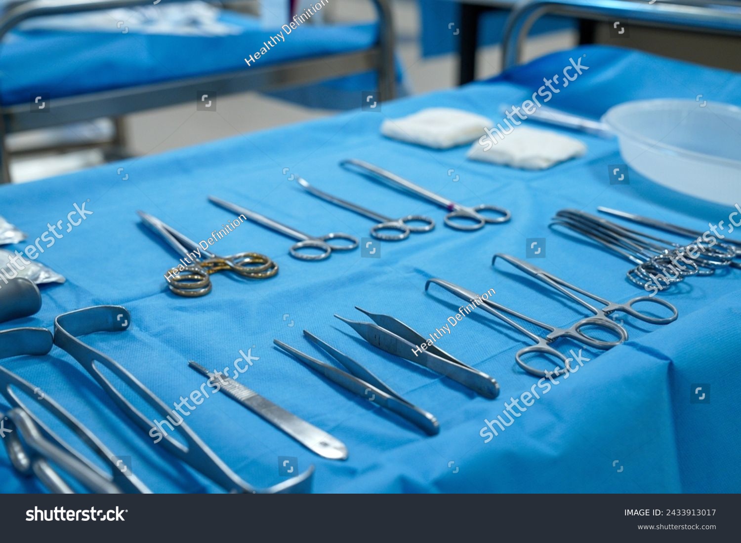 Sterile surgical instruments and tools including scalpels, scissors, forceps and tweezers arranged on a table for a surgery, Sterilized surgical instruments on the blue wrap	 #2433913017