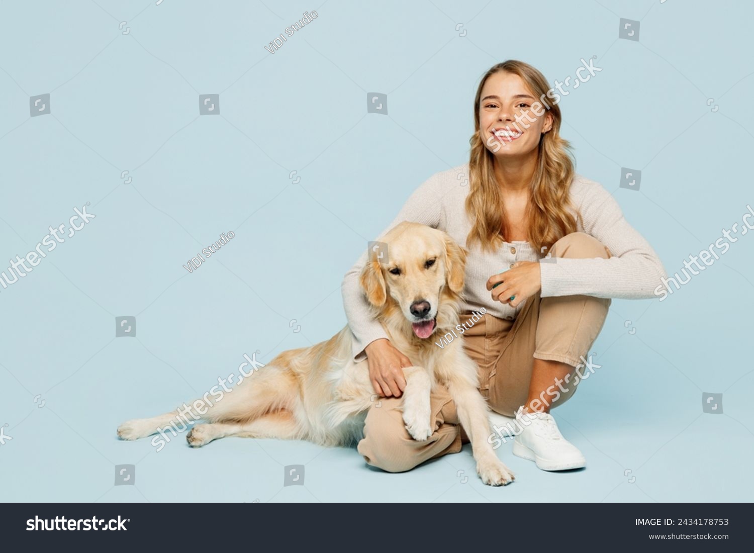 Full body smiling happy young owner woman wearing casual clothes sitting hug cuddle embrace her best friend retriever dog isolated on plain light blue background studio. Take care about pet concept #2434178753