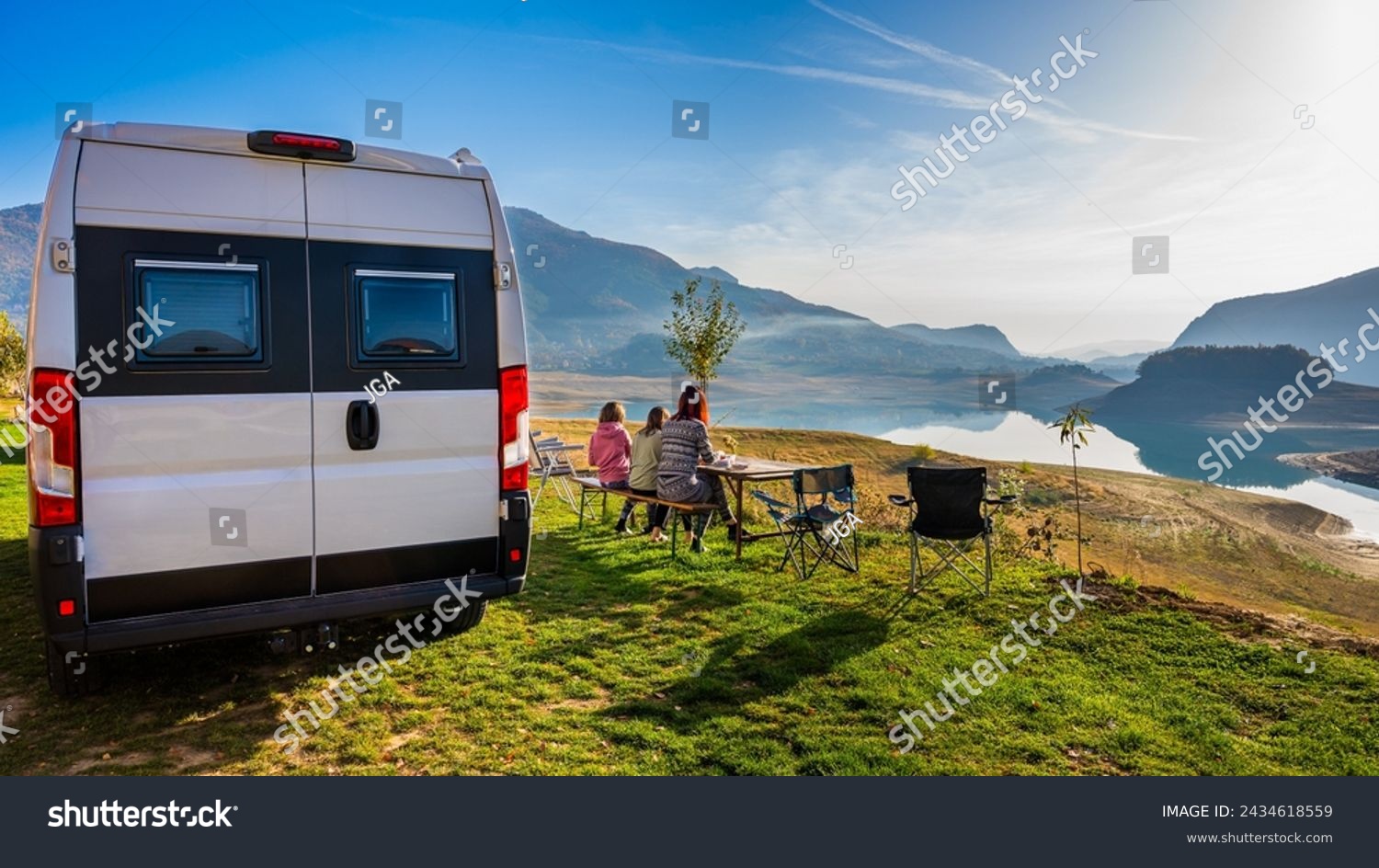 Campervan, Motorhome RV parked next to the lake or river in Bosnia and Herzegovina. Family with camper van or motor home eating breakfast on an active family vacation on a road trip to Ramsko lake. #2434618559
