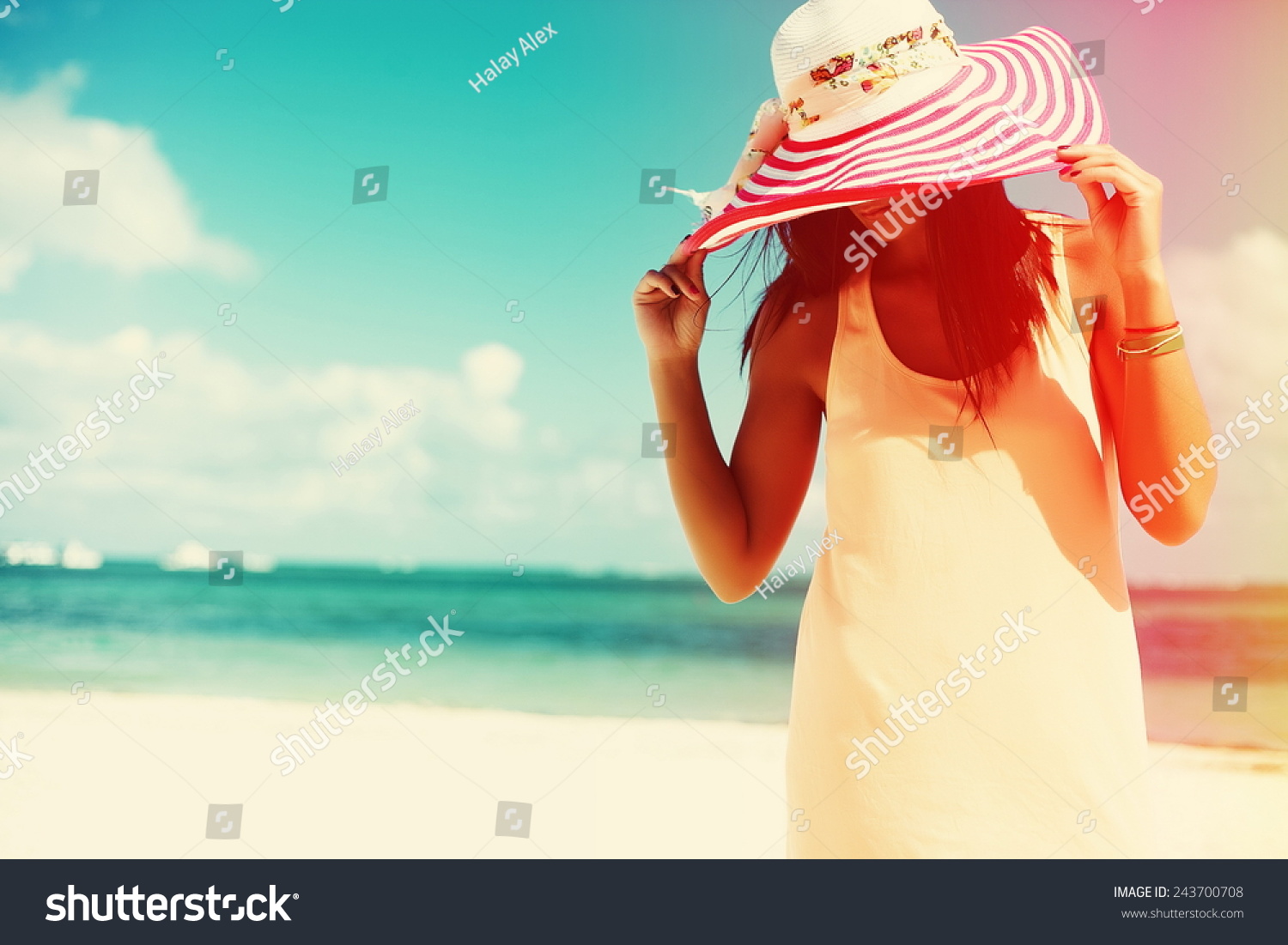 Hot beautiful woman in colorful sunhat and dress walking near beach ocean on hot summer day on white sand #243700708