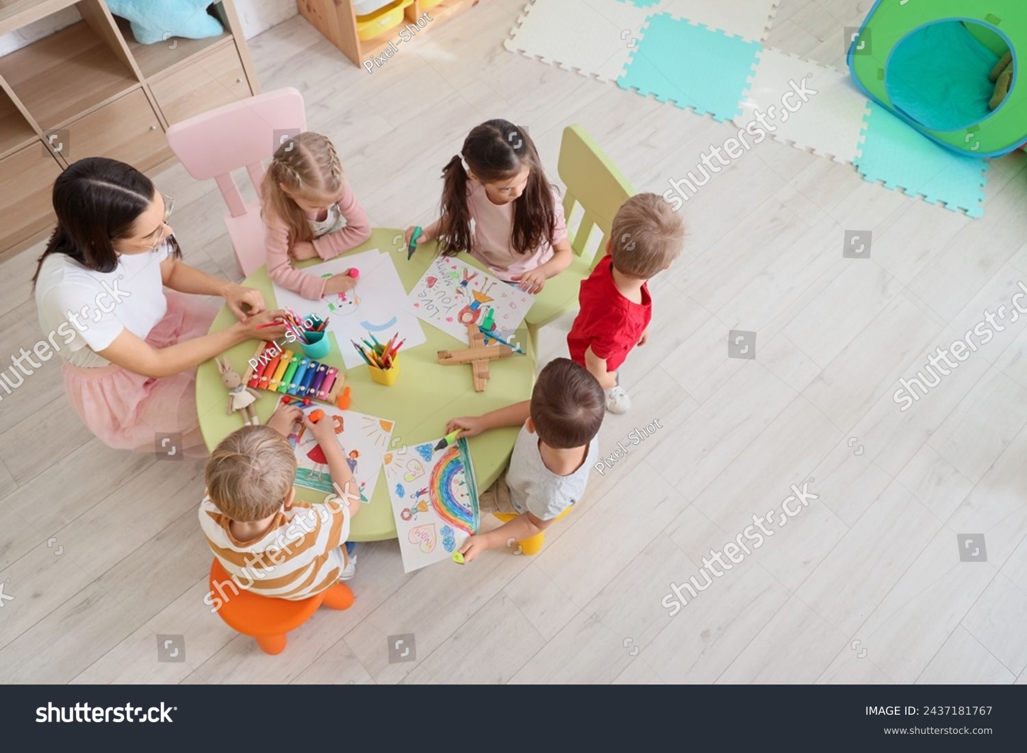 Little children with nursery teacher drawing at table in kindergarten, top view #2437181767