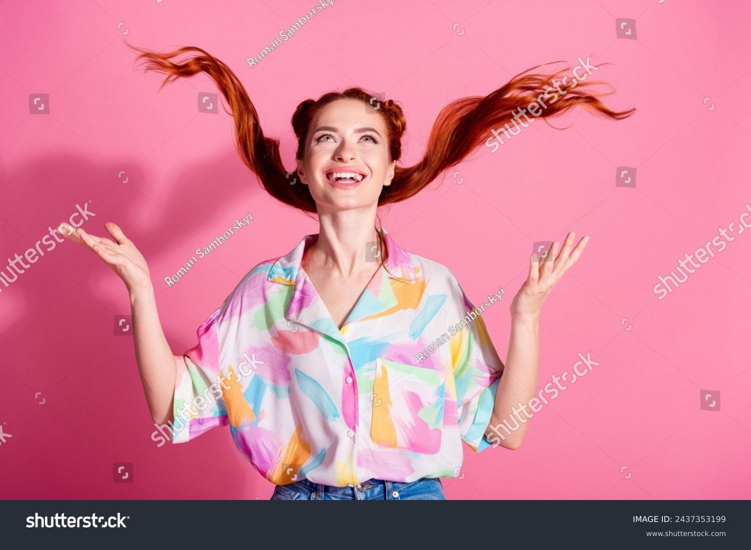 Portrait of cheerful woman wear print shirt hands fluttering foxy hair look up at logo empty space isolated on pink color background #2437353199