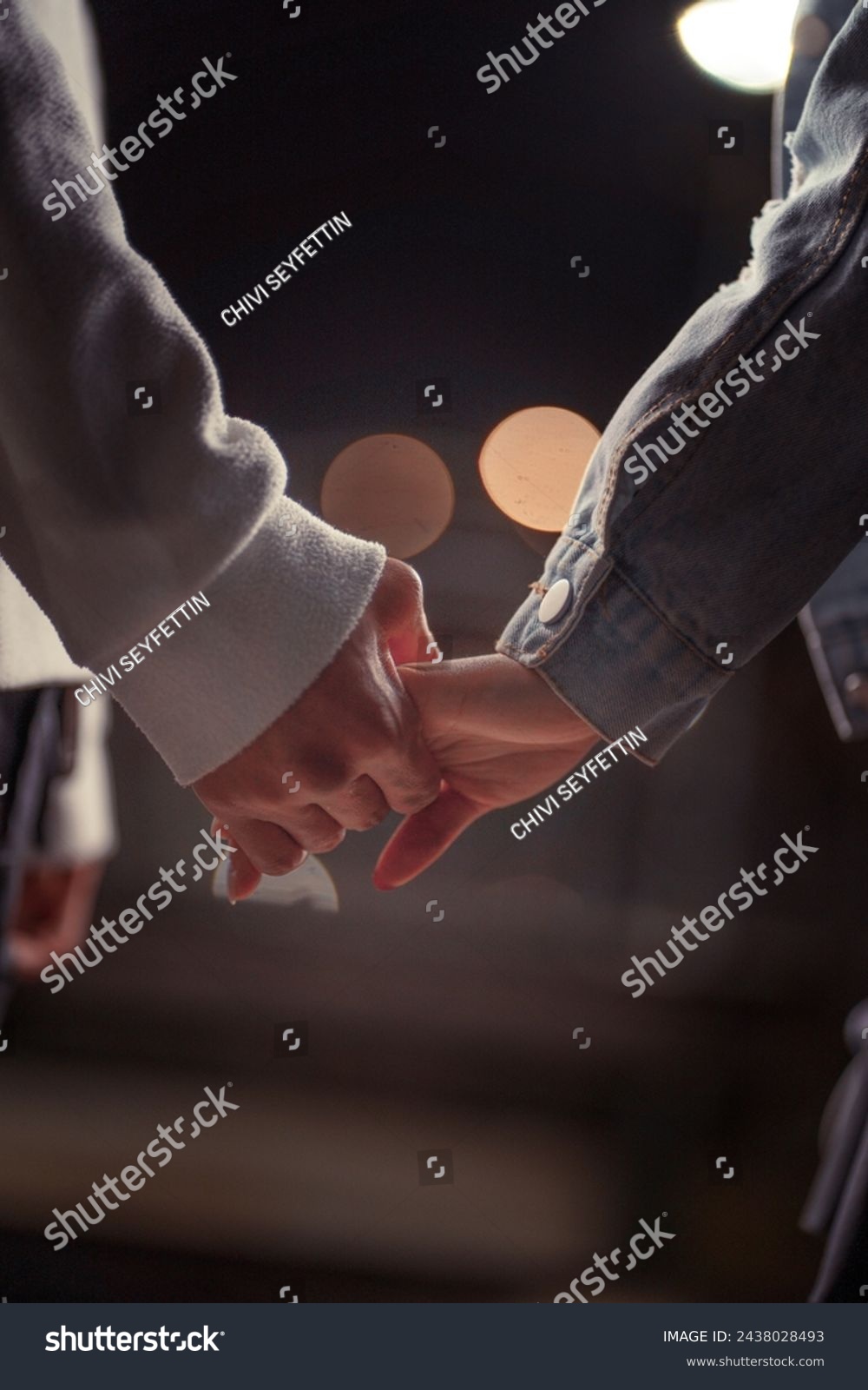 A close-up of a couple's clasped hands, set against a backdrop of soft light, evokes the closeness and warmth of their connection. #2438028493