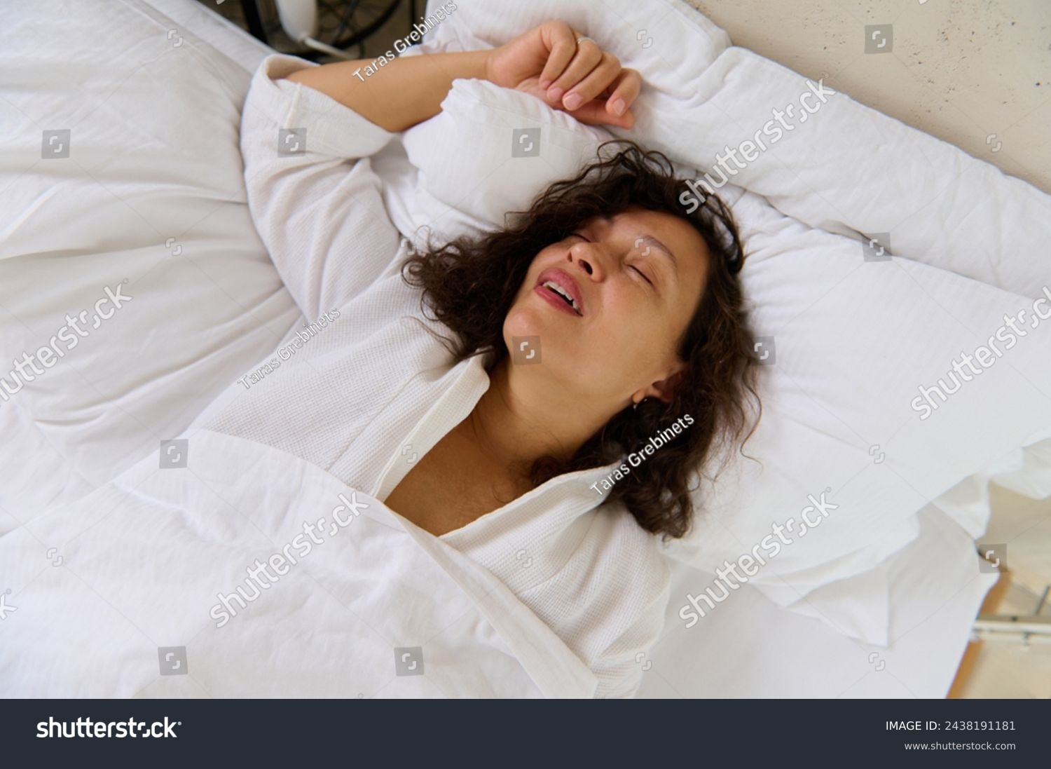 Close-up of a young woman snoring while sleeping in her bed. Snoring problems. Multi ethnic young adult woman having insomnia and health problems, falling asleep in her bed in bedchamber #2438191181
