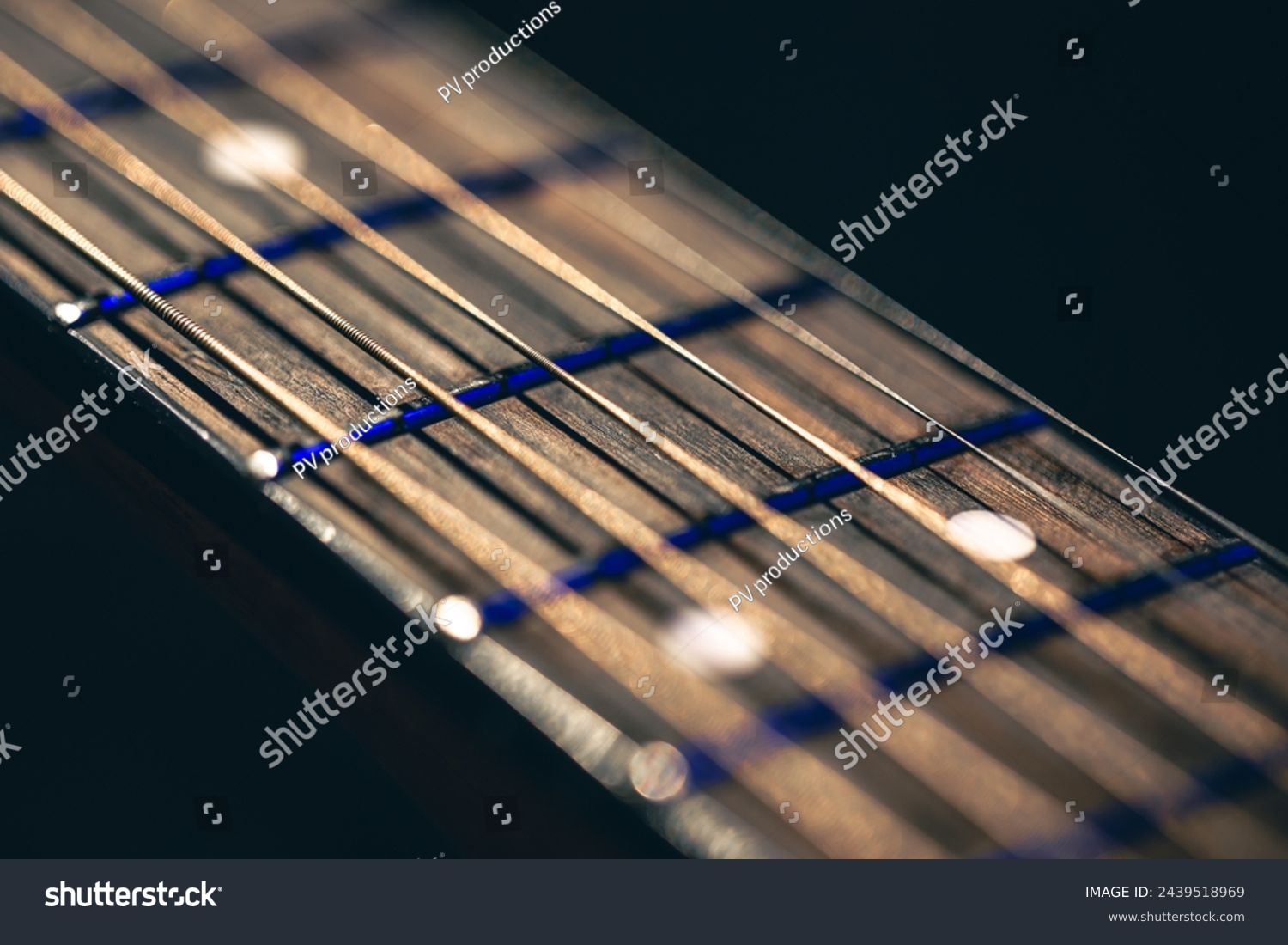Part of an acoustic guitar, guitar fretboard on a black background. #2439518969