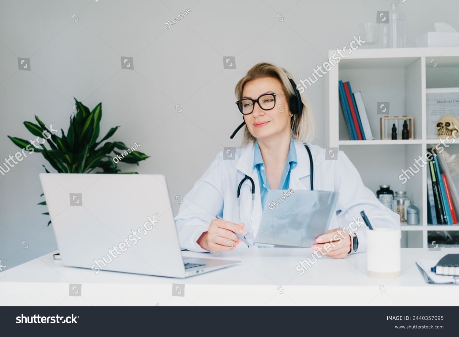 Female doctor in headset make online video call consult patient on laptop. Middle aged woman therapist videoconferencing for domestic health treatment. Telemedicine. Online remote medical appointment. #2440357095