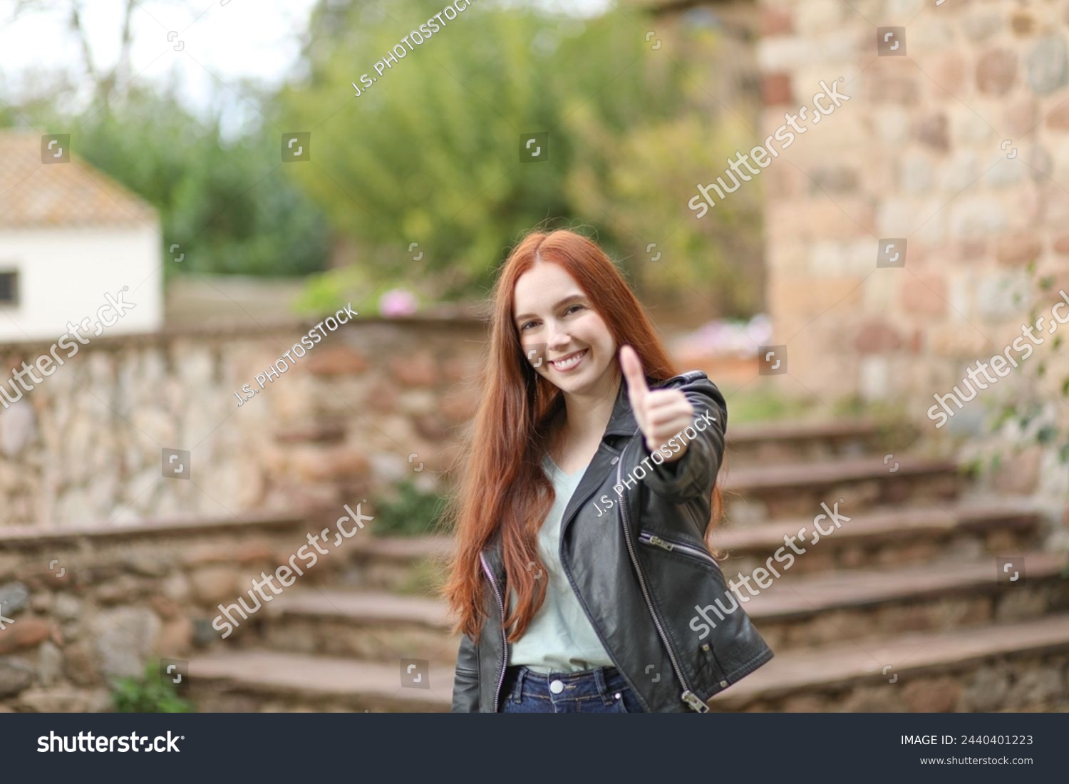 Young woman with long hair extends her hand and raises her thumb giving her approval #2440401223