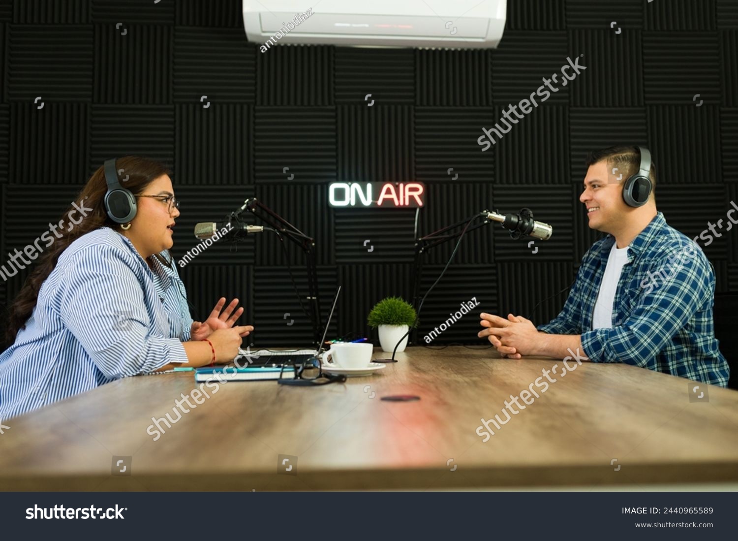 Cheerful podcast co-hosts smiling looking happy while recording an episode of their talk show at the radio studio #2440965589