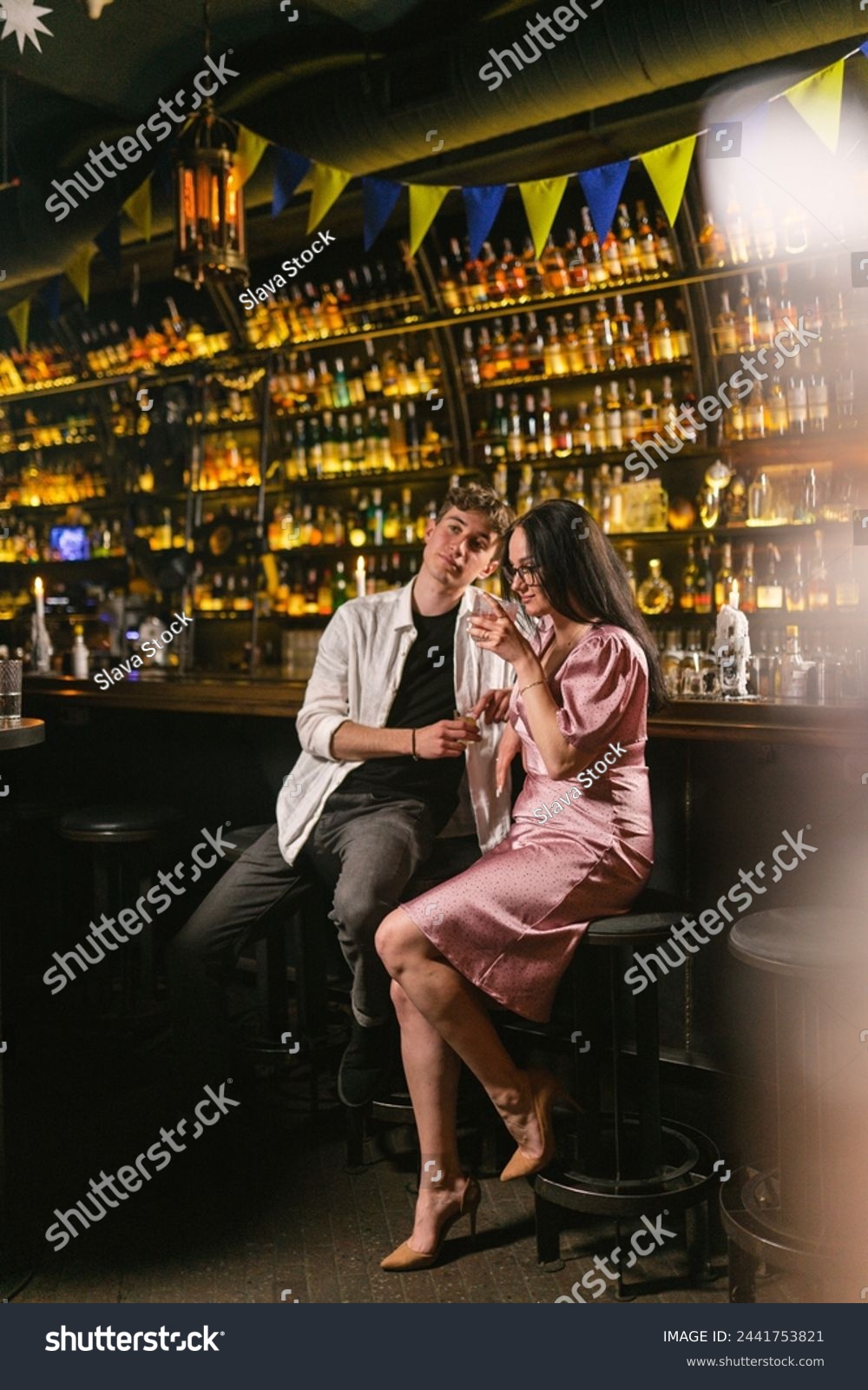 Pretty woman in pink dress and young man meet in fancy bar. Romantic date of lovely couple in Ukrainian pub. Love relationship #2441753821