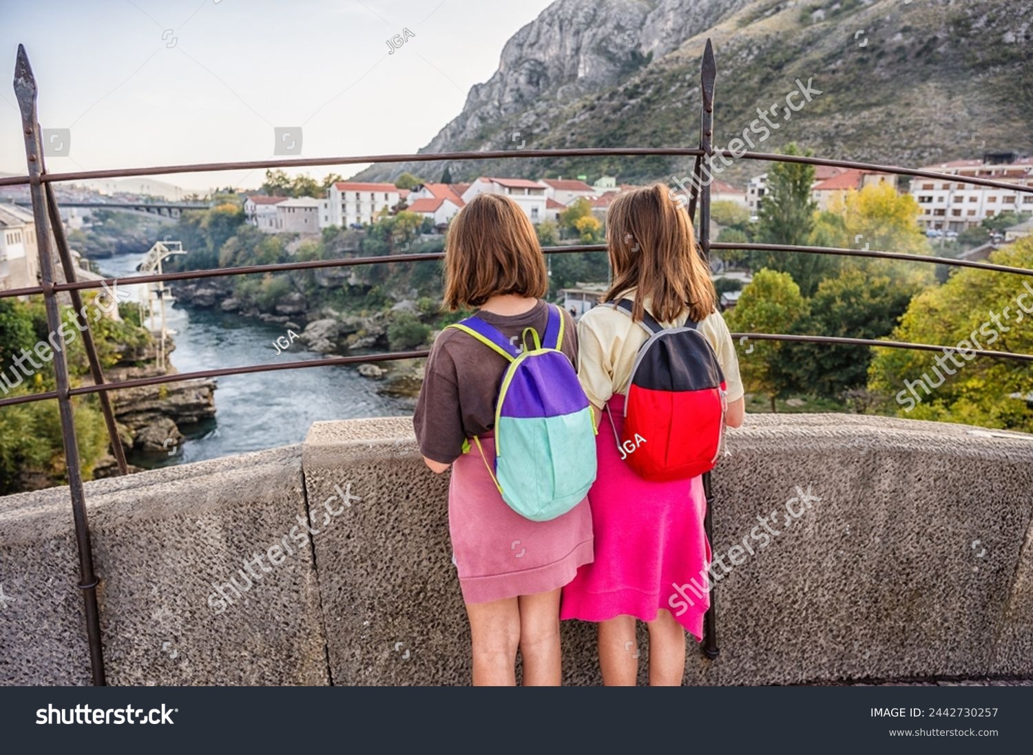 Twin girls standing on famous Mostar bridge, looking at Mostar town and river Neretva in Bosnia and Herzegovina. Historical Mostar Bridge known also as Stari Most or Old Bridge in Mostar. #2442730257