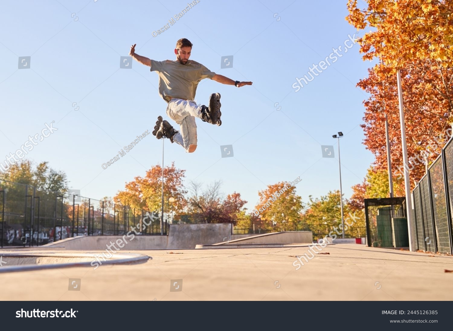young male roller skater jumping and doing a trick with his inline skates. #2445126385