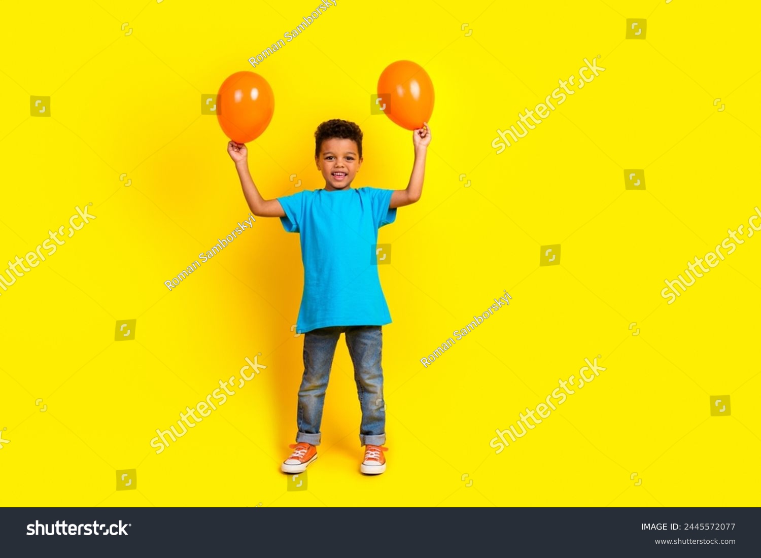Full size photo of multiethnic multinational boy wear blue t-shirt denim pants raising up balloons isolated on vivid yellow background #2445572077