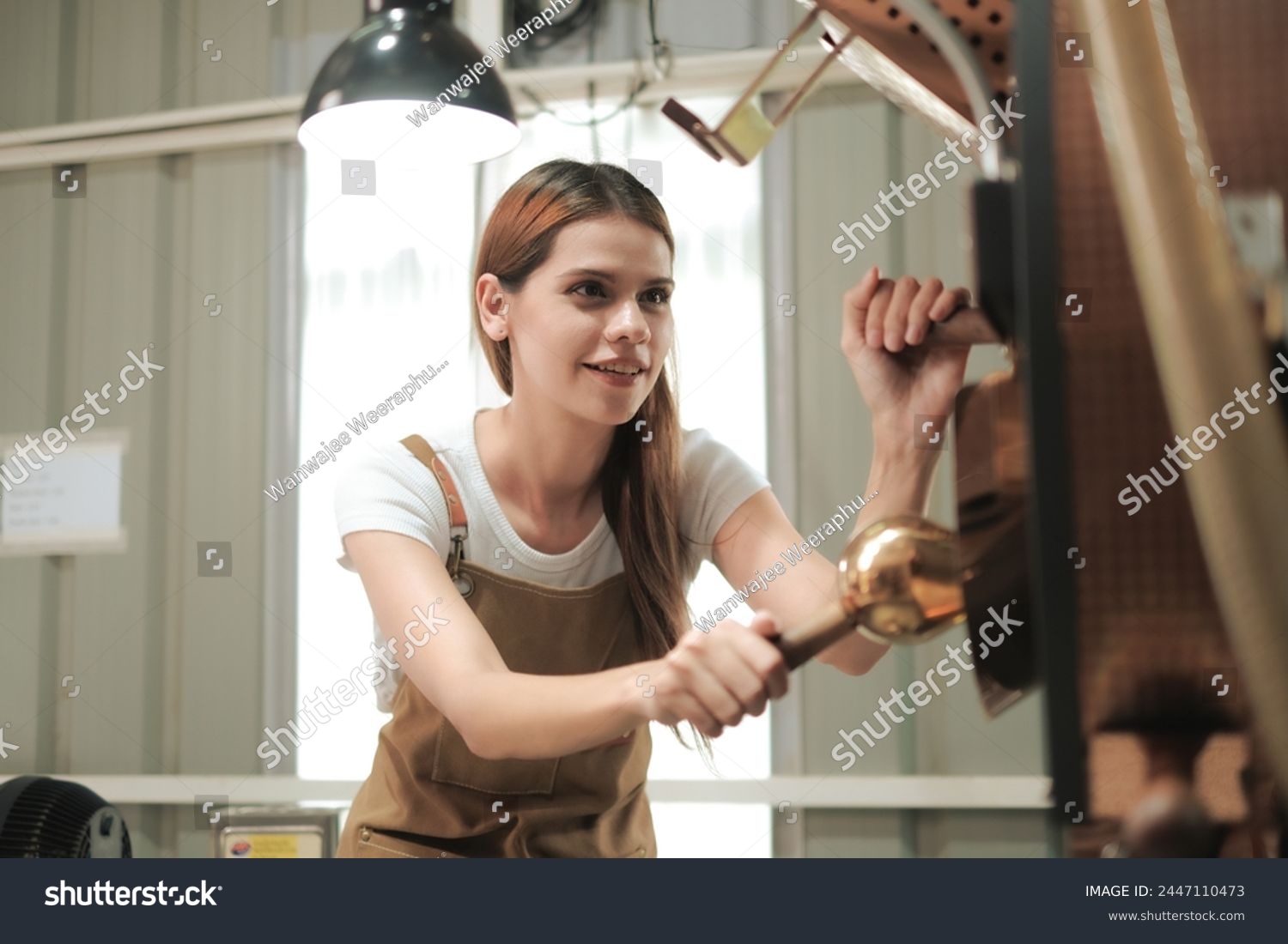 White woman craftsperson using roasted coffee beans machine with smile of happiness, Woman work in roasted coffee beans manufactory. #2447110473