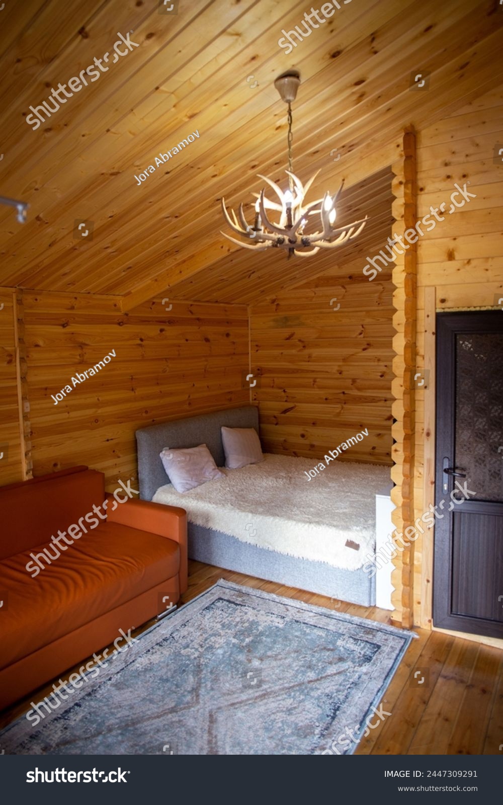 The cabins interior is paneled with wood and furnished with a bed, sofa, and armoire. A bearskin rug adds a touch of warmth to the space. #2447309291