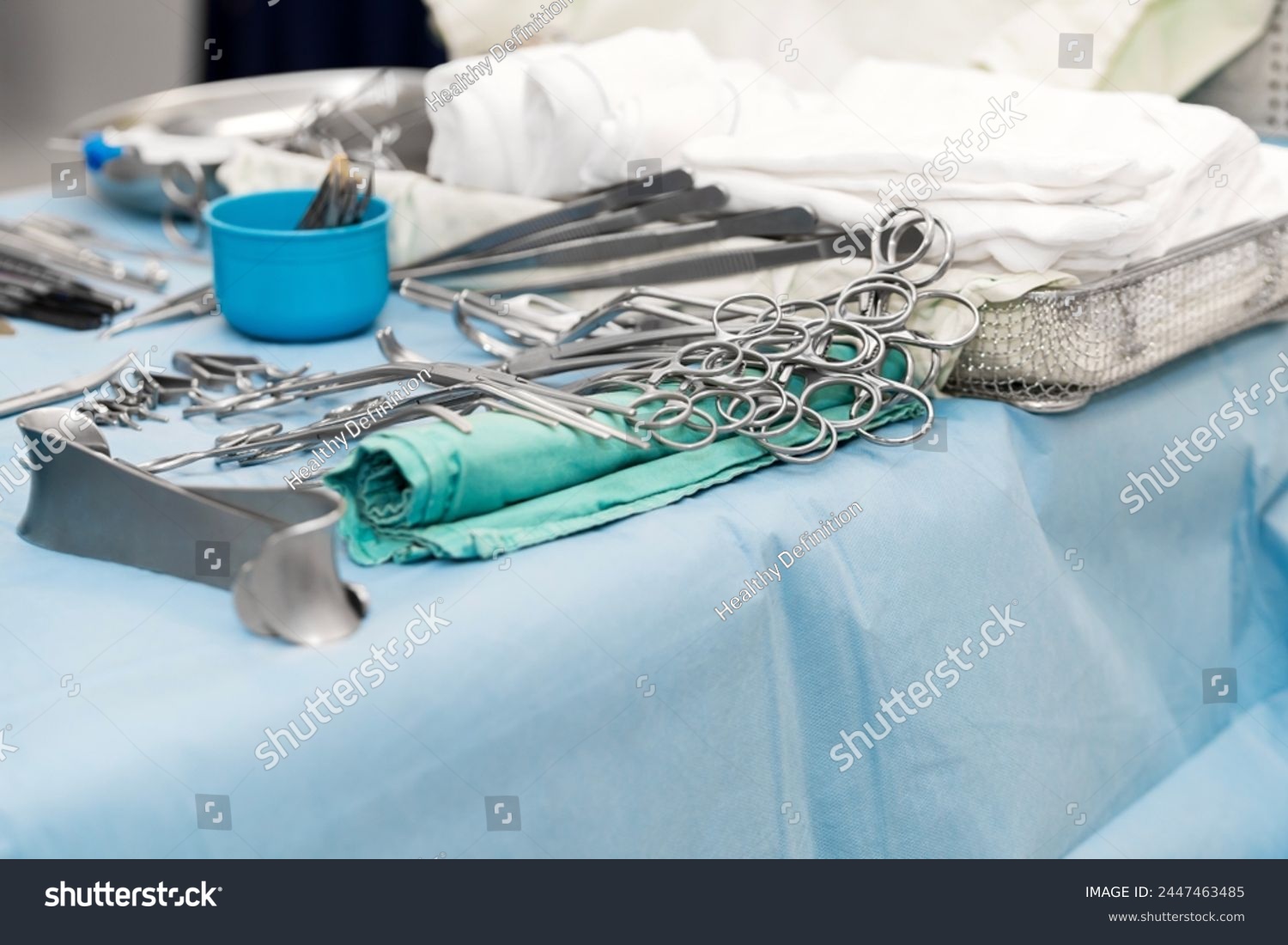 Sterile surgical instruments and tools including scalpels, scissors, forceps and tweezers arranged on a table for a surgery, Sterilized surgical instruments on the blue or green wrap	 #2447463485