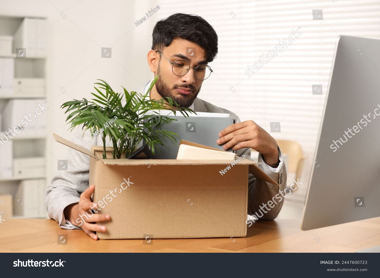 Unemployment problem. Frustrated man with box of personal belongings at desk in office #2447600723