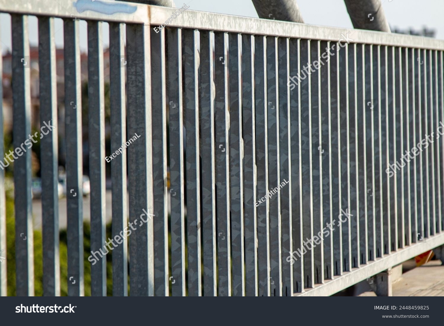 Close-up view of the steel structure of a modern bridge. Close-up of metal fence on the street. Detail of a steel bridge with blue sky in the background. #2448459825