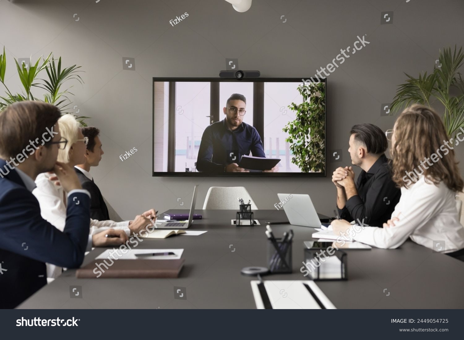 Arabic businessman speaker hold video conference for staff using application. Group of interested business people, employees listening speech, information, opinion of male boss shown on monitor screen #2449054725