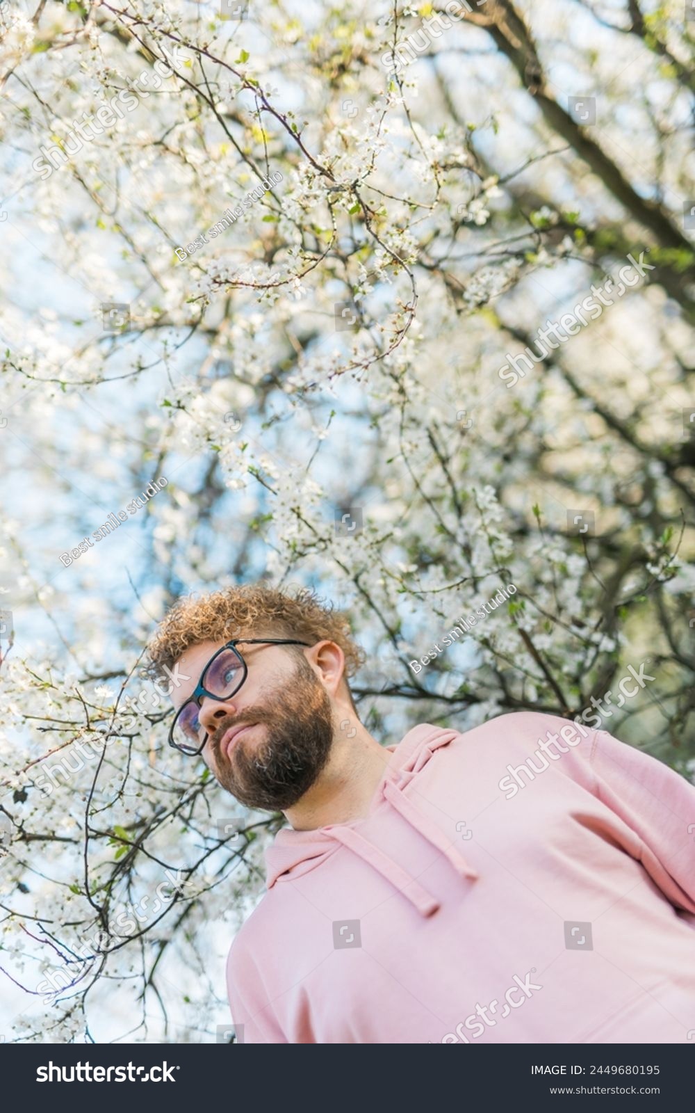 Handsome man outdoors portrait on background cherry blossoms or apple blossoms. Millennial generation guy and new masculinity concept #2449680195