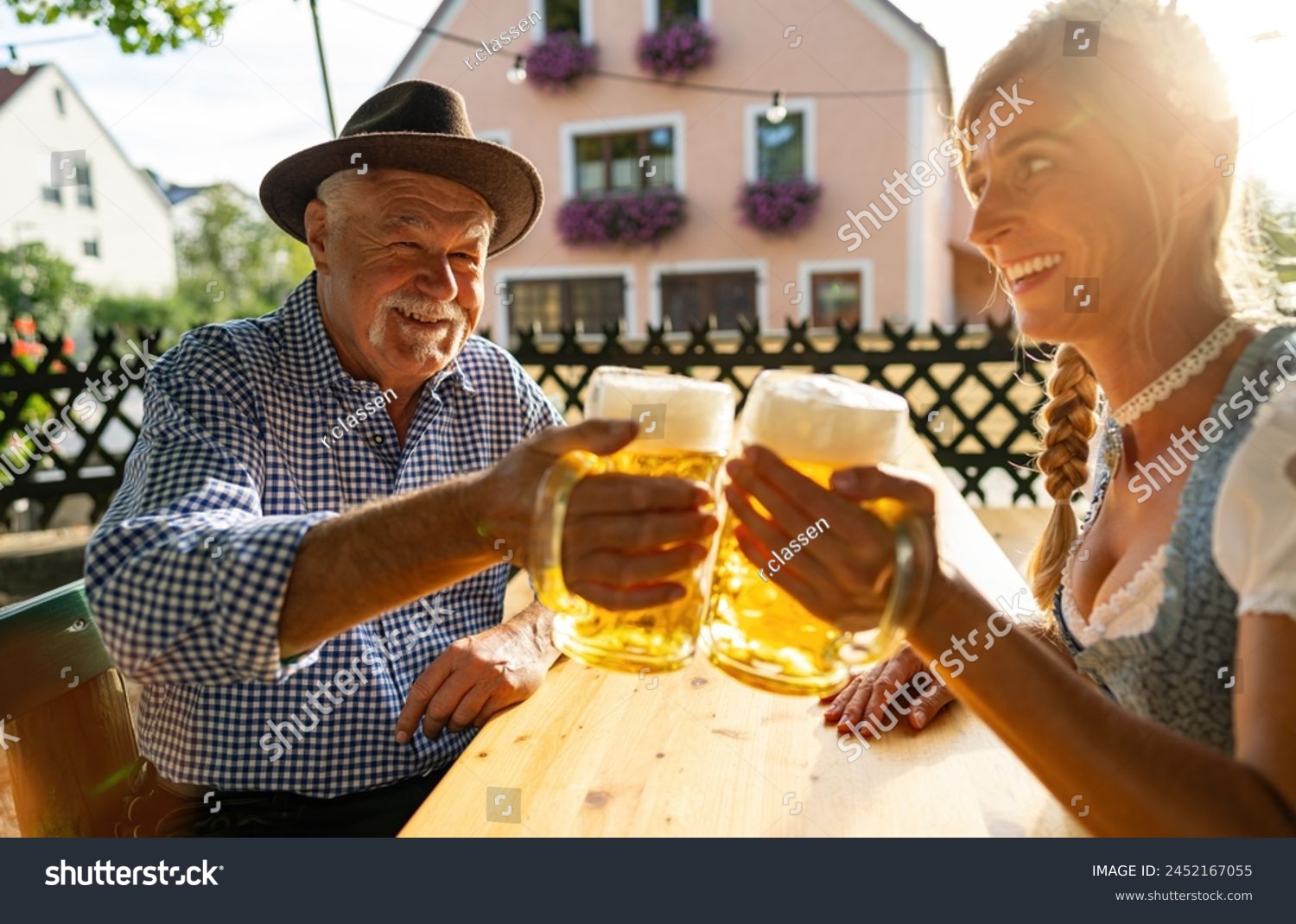 Senior man and woman in traditional clothing or tracht toasting beer mugs in beer garden or oktoberfest at Bavaria, Germany #2452167055