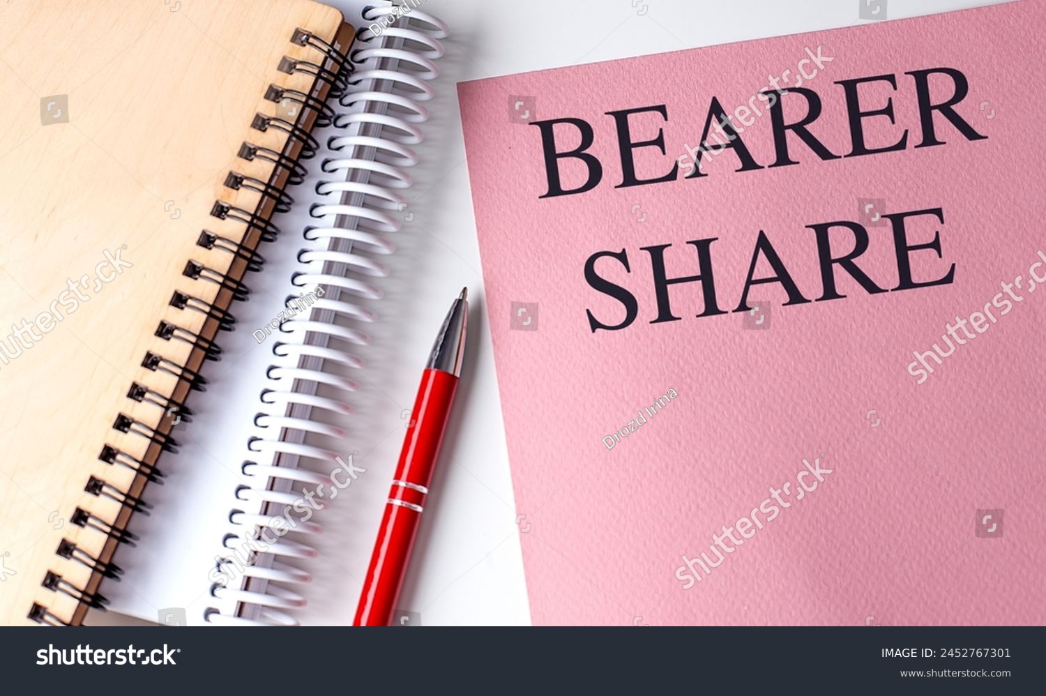 BEARER SHARE text on a pink paper with notebooks .  #2452767301