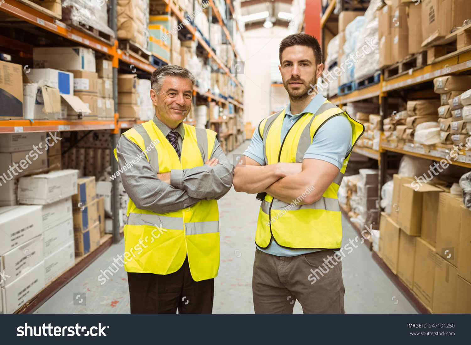 Warehouse team standing with arms crossed in a large warehouse #247101250