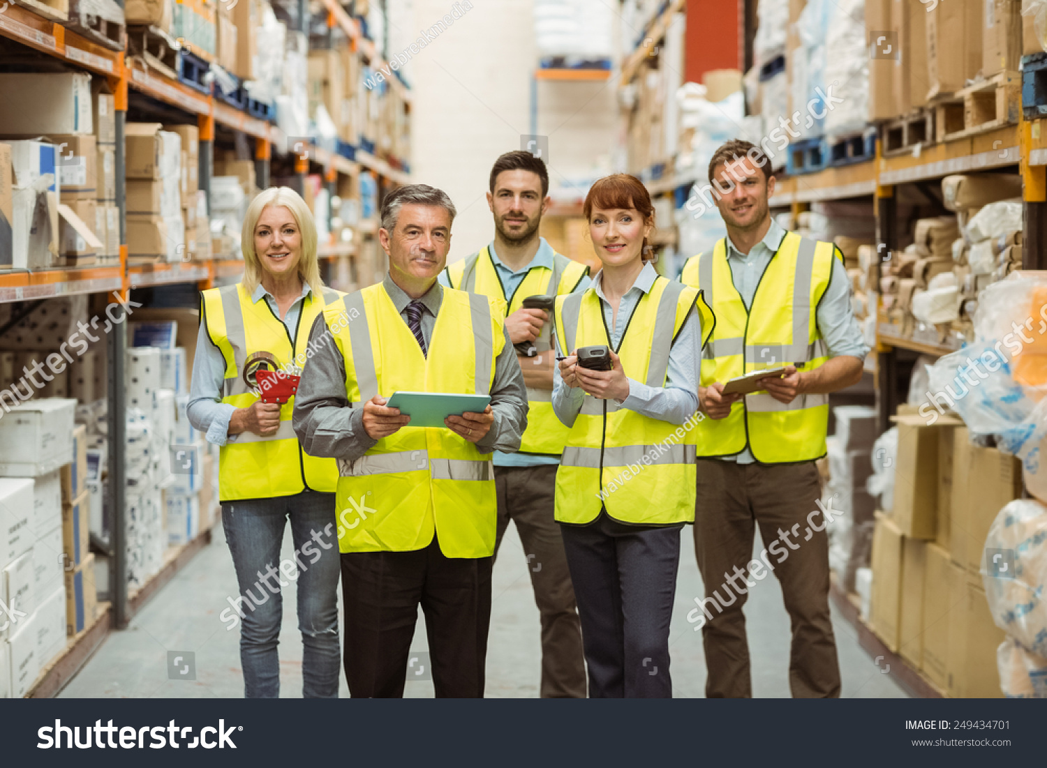 Smiling warehouse team looking at camera in a large warehouse #249434701